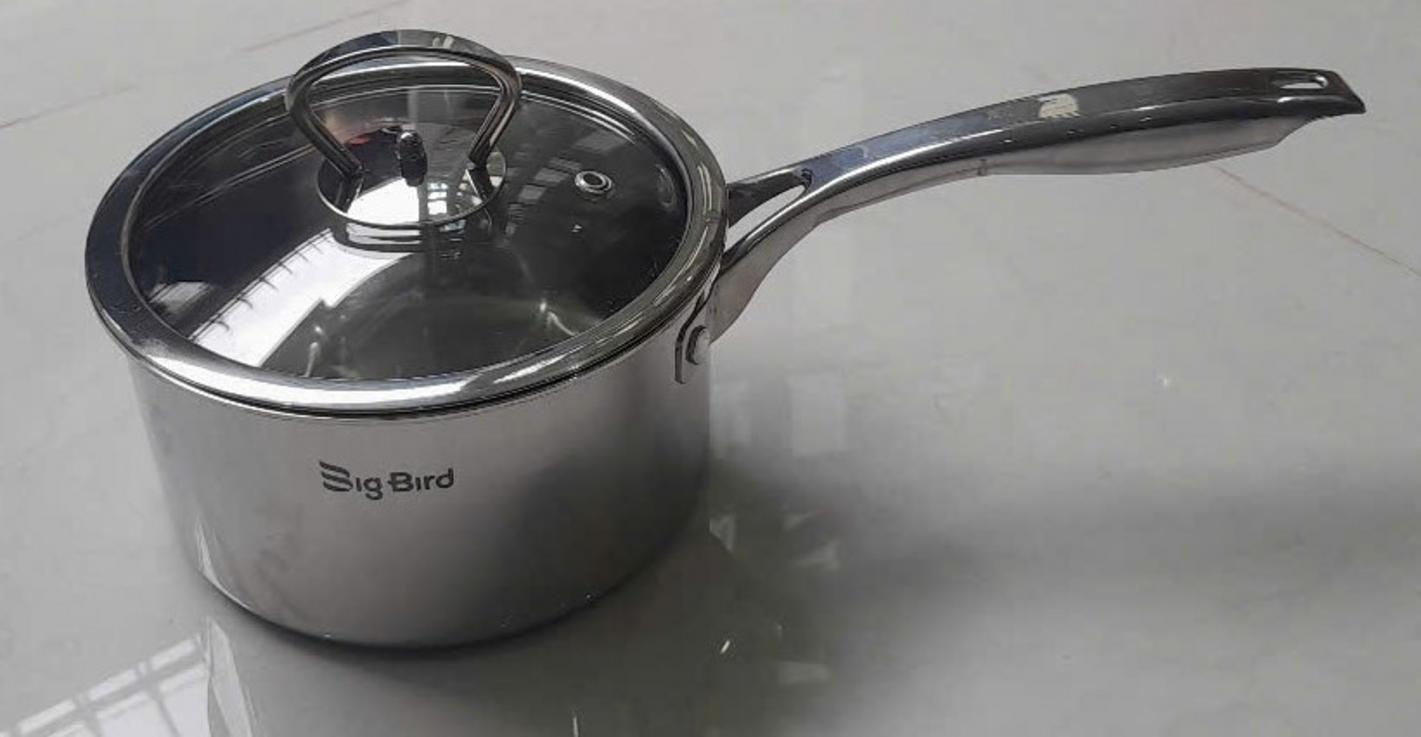 a stainless steel cooking pot with glass lid on kitchen stove