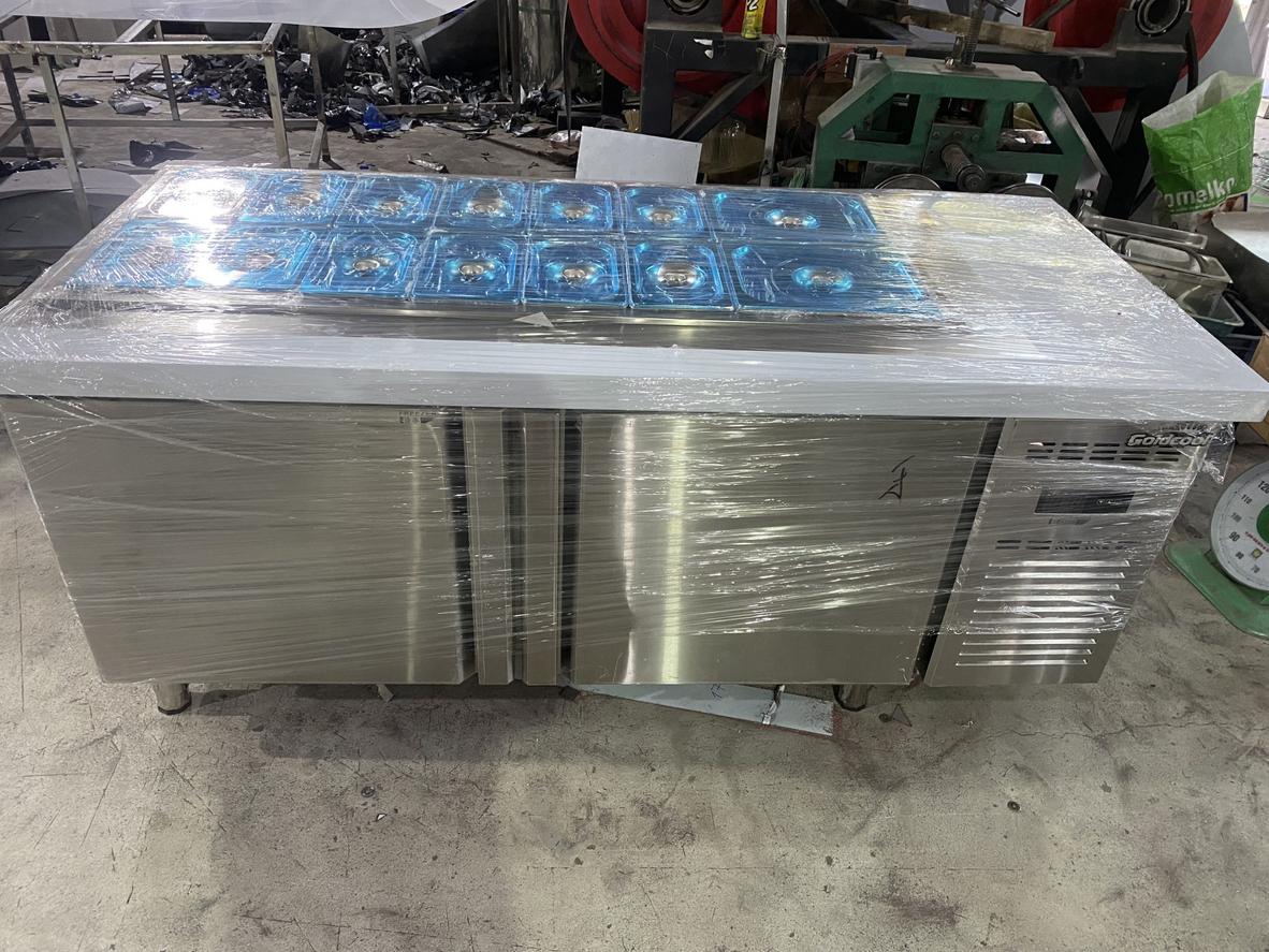 Nhân viên bếp thao tác nhanh chóng và hợp vệ sinh trên một line salad được tổ chức tốt.