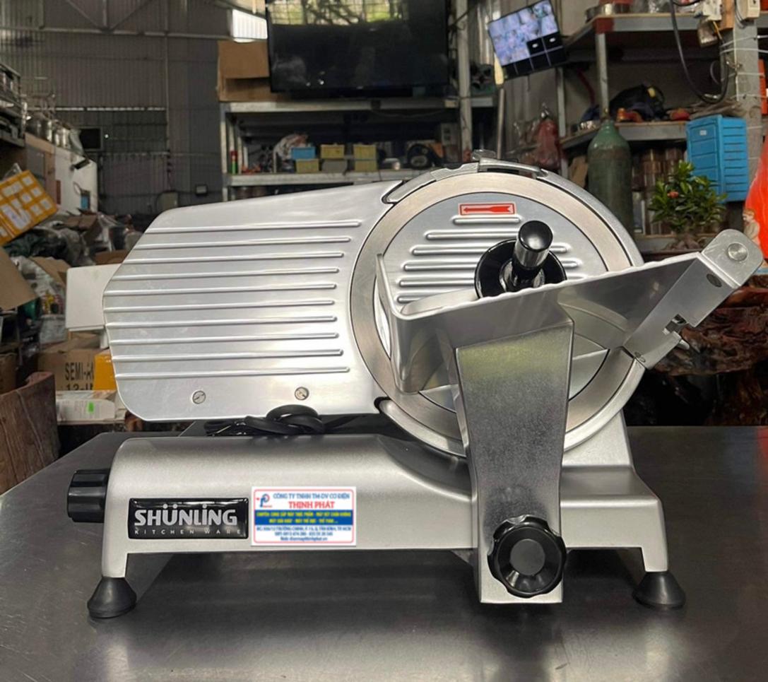 Kỹ thuật viên đang thực hiện vệ sinh và bảo dưỡng một máy xay thịt công nghiệp.