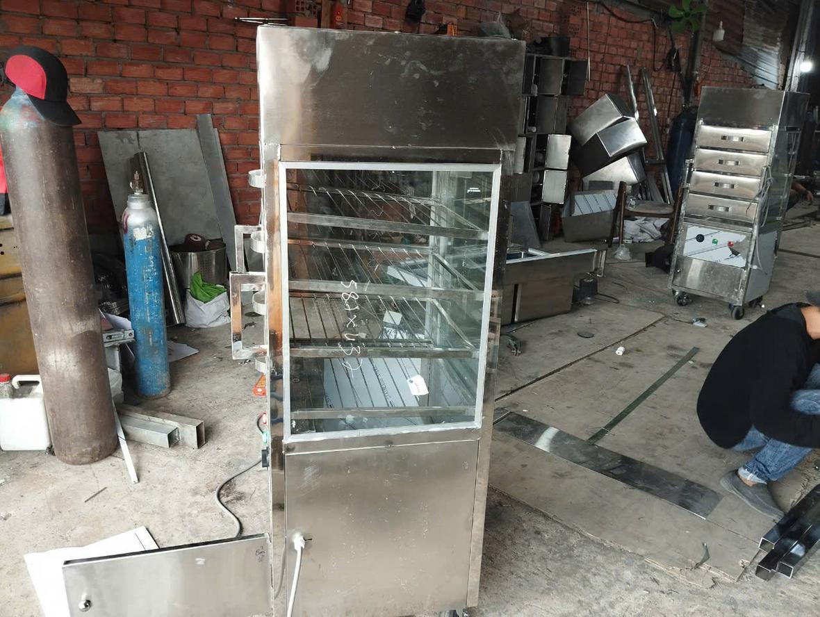 Nhân viên đang thực hiện vệ sinh khoang trong của tủ hấp bánh bao.