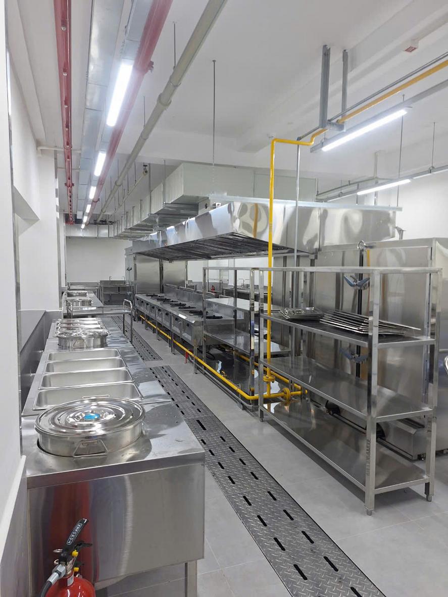 Nhân viên bếp đang thực hiện quy trình vệ sinh mương và vỉ thoát sàn inox cuối ngày.