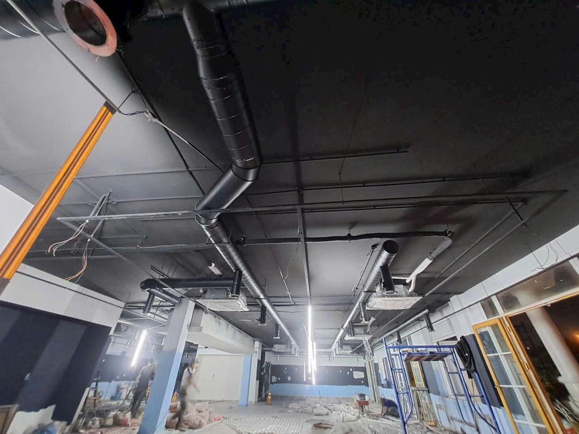 Kỹ thuật viên đang tiến hành lắp đặt hệ thống chụp hút khói tại một dự án nhà hàng.